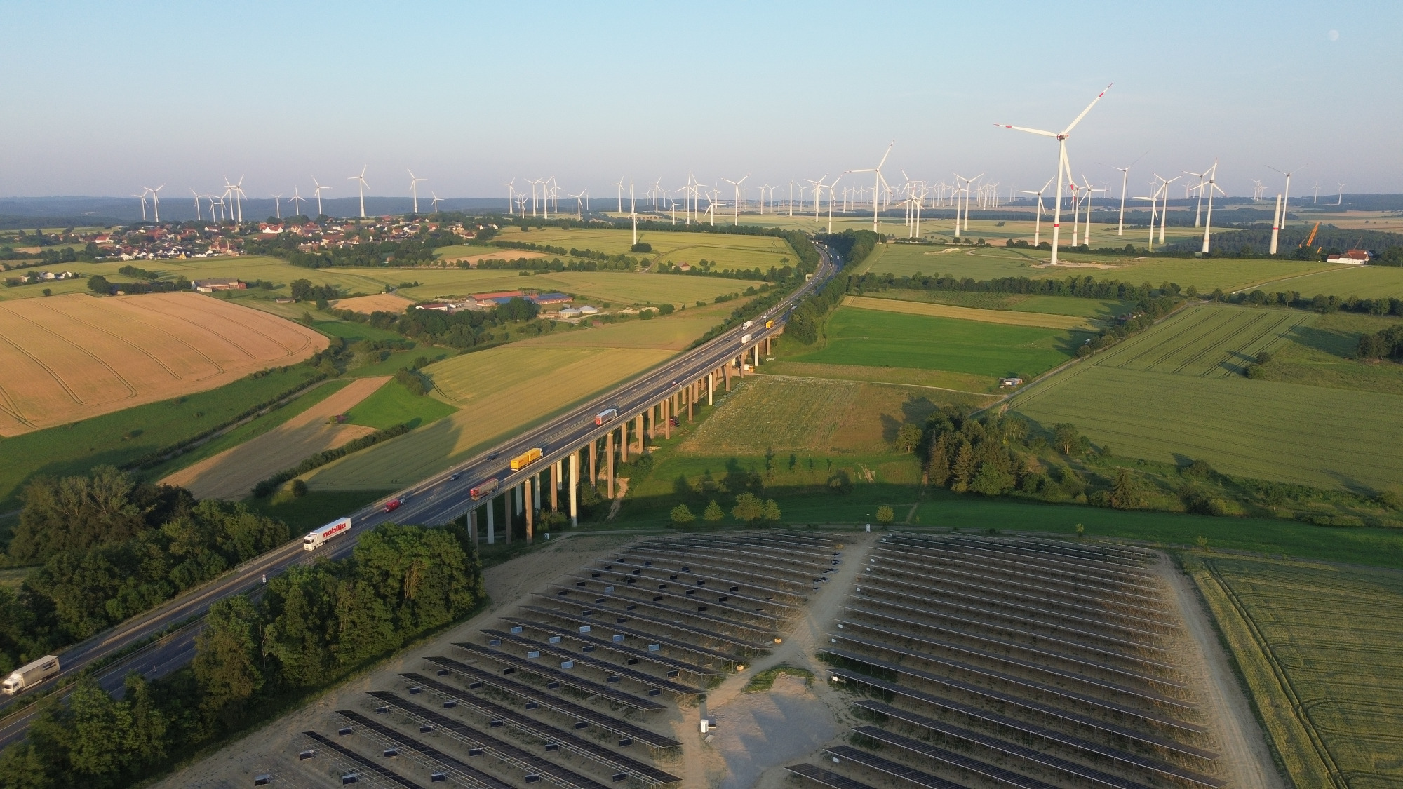 PV-Standort mit Talbrücke und Windpark im Hintergrund