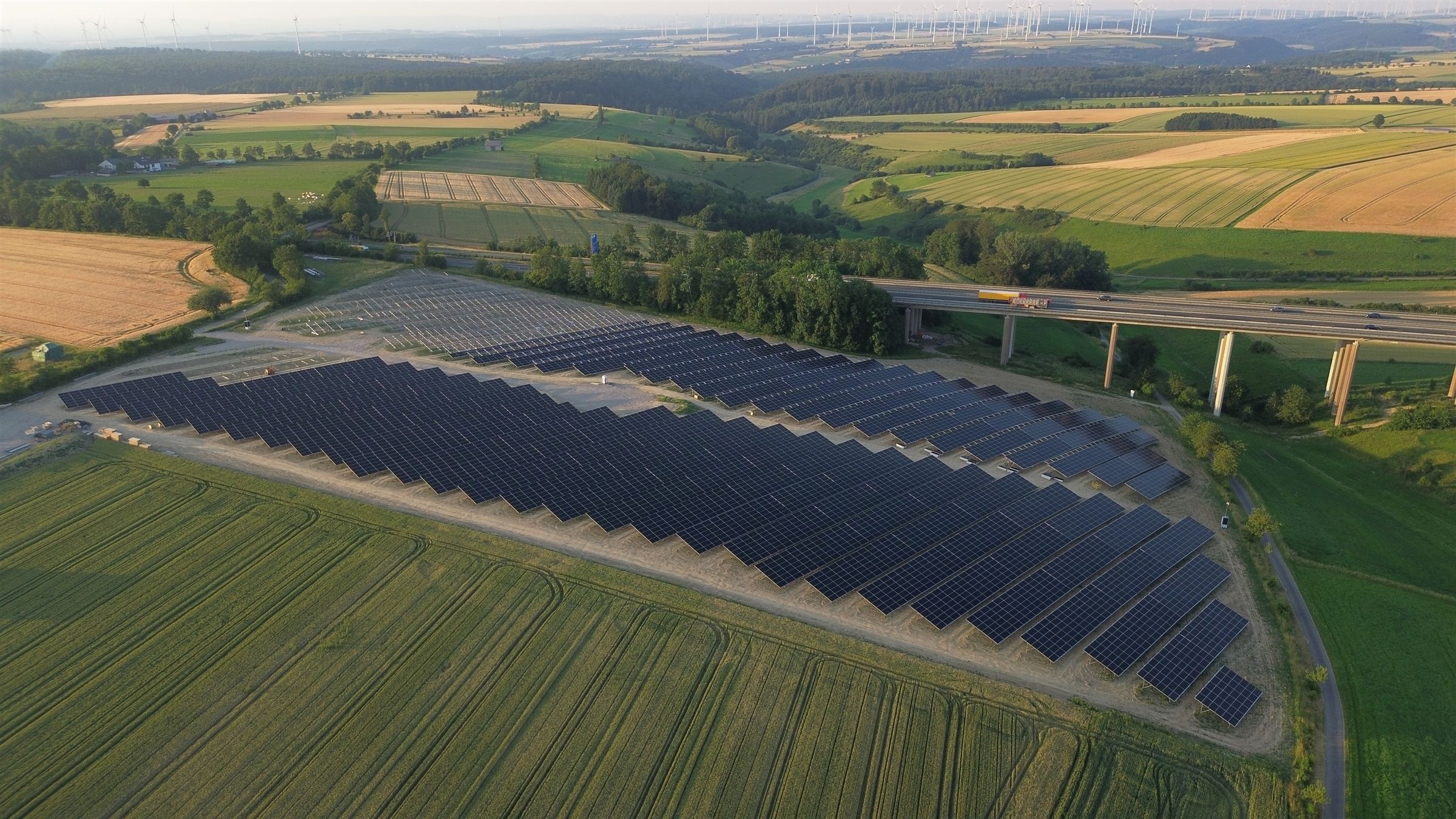 Solarpark am Autobahnkreuz Wünnenberg-Haaren mit Autobahnviadukt und Windpark im Hintergrund